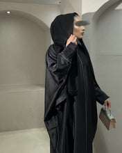 Load image into Gallery viewer, Side view of black satin abaya featuring smooth texture and piping