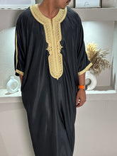Load image into Gallery viewer, Male model wearing elegant black Moroccan thobe with gold trim