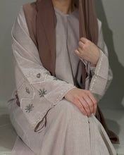Load image into Gallery viewer, Close-up view of nude pink abaya showing intricate handmade sleeve embellishment
